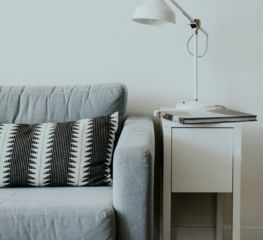 white study lamp on top of white wooden end table beside gray fabric sofa
